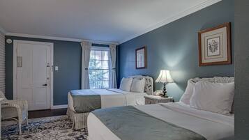 A bedroom with two beds, a window with curtains, a chair, and a nightstand with a lamp.