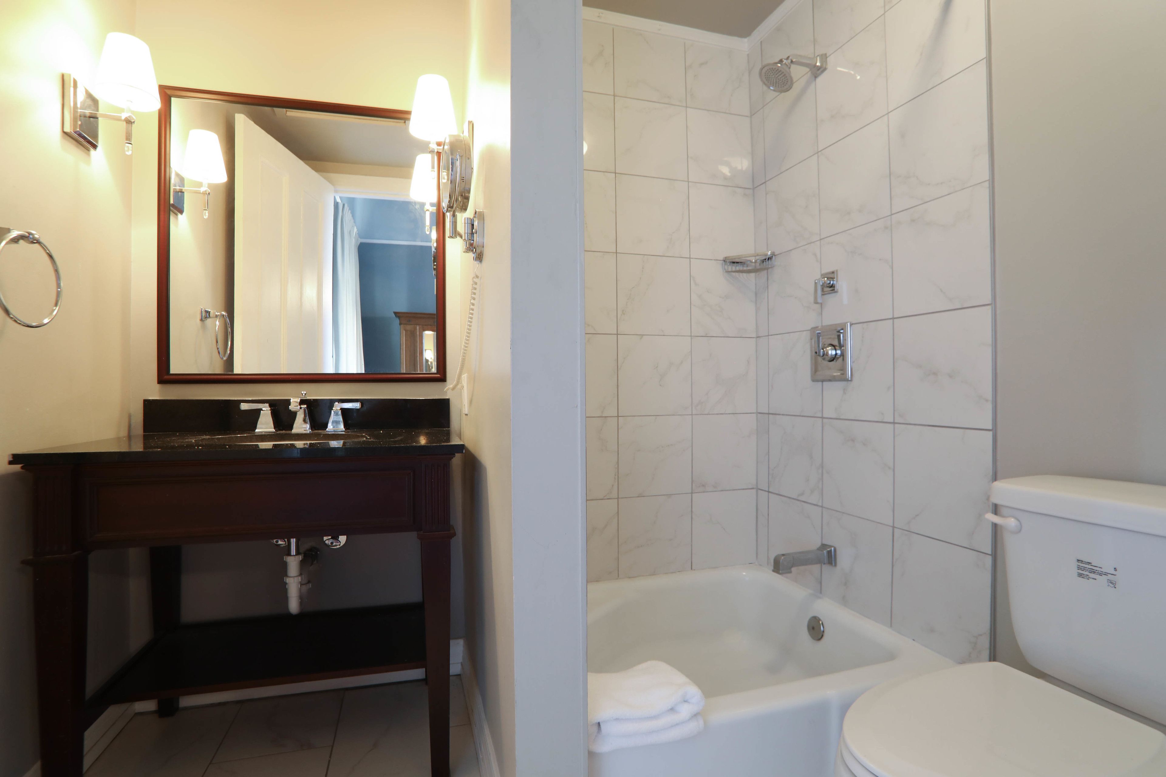 A bathroom with a sink, mirror, and a bathtub.
