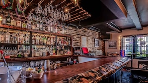 A bar with wooden shelves stocked with liquor bottles, a bar counter, and a cushioned bench.