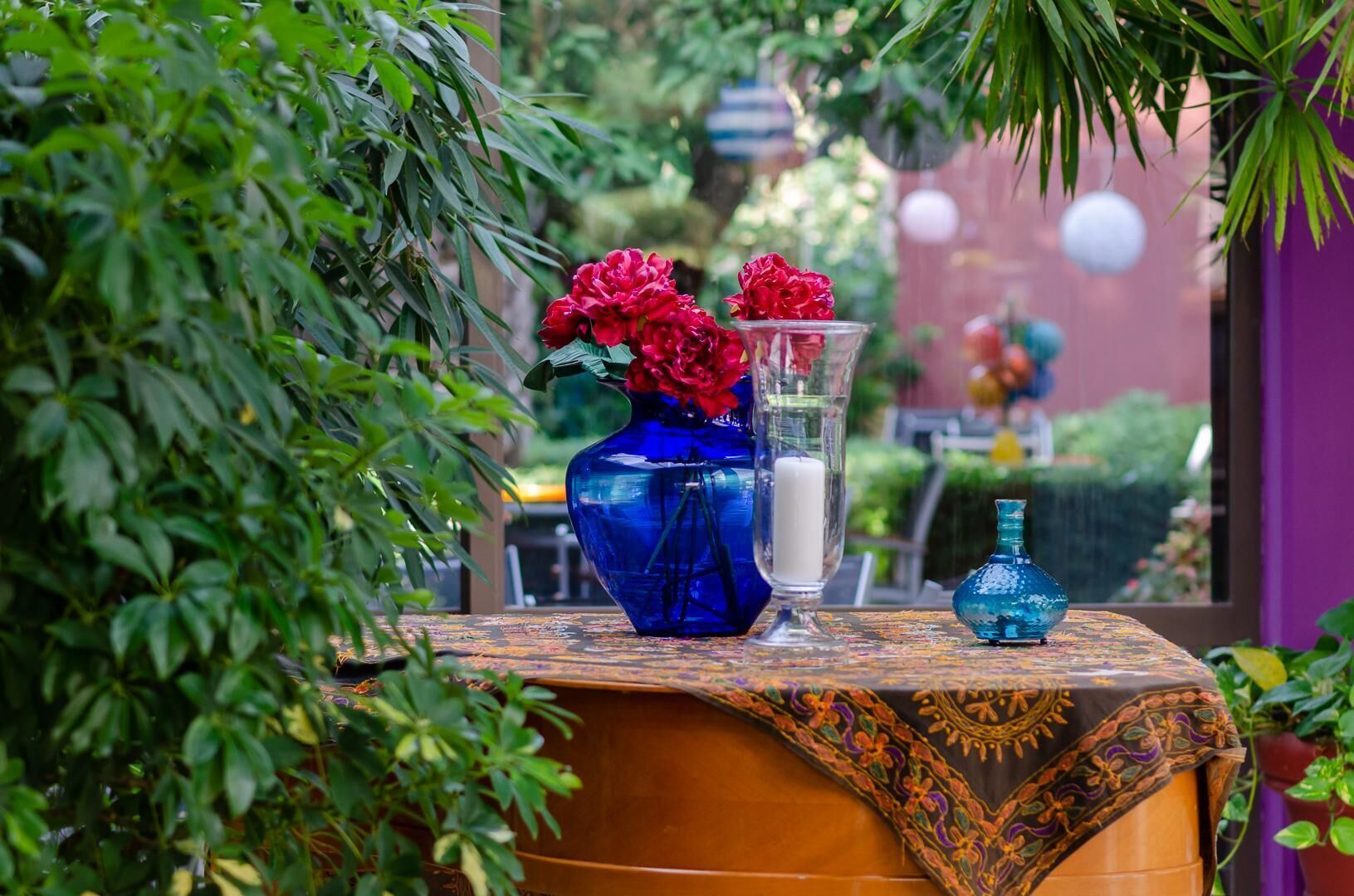 A table with a blue vase, a clear vase, and a candle.