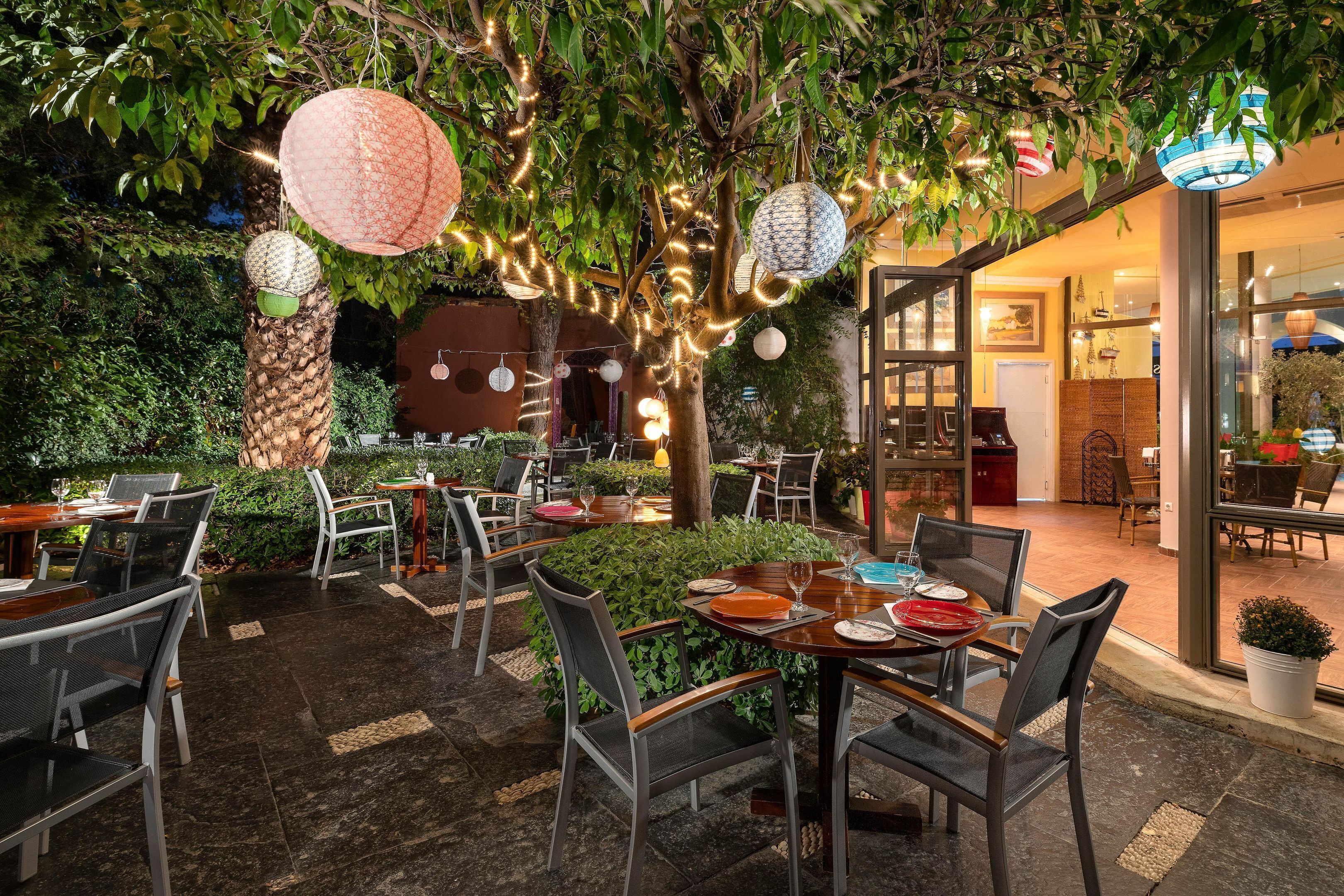 Un espace de restauration en plein air avec des tables et des chaises, des guirlandes lumineuses et des lanternes suspendues.
