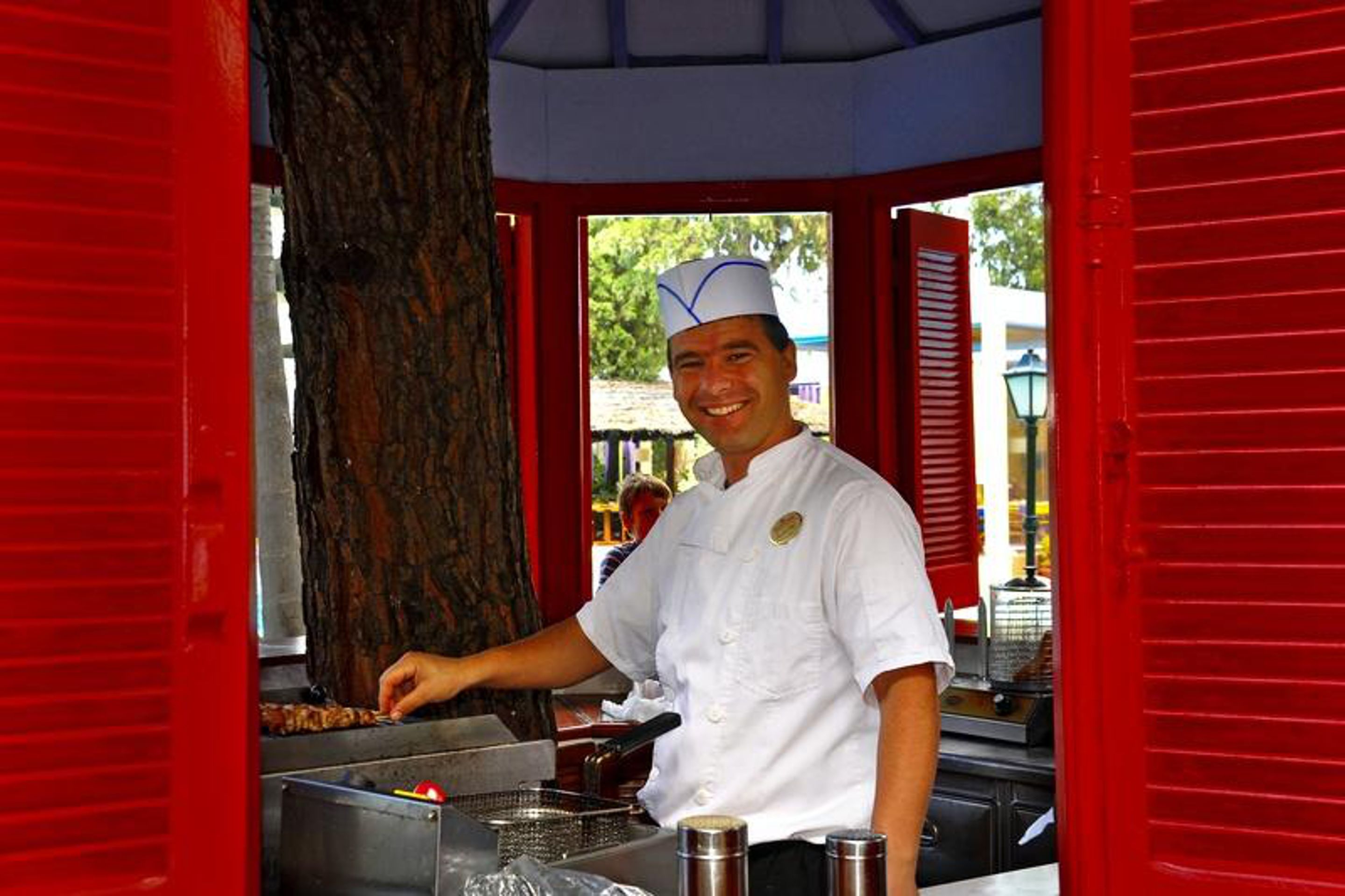 Un chef con uniforme blanco asando comida en una estructura rojo y blanco.