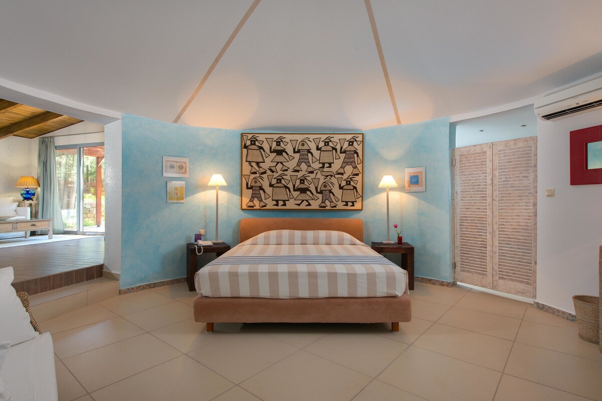 Un dormitorio con una cama grande, dos lámparas de noche, una obra de arte en la pared y un armario con puerta corredera.