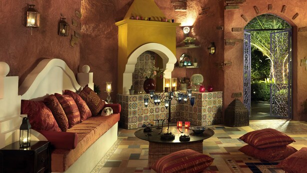 A traditional interior with a thatched roof, a sofa with cushions, a patterned floor, and a decorative archway. - Dionysos Hotel (Rhodes)