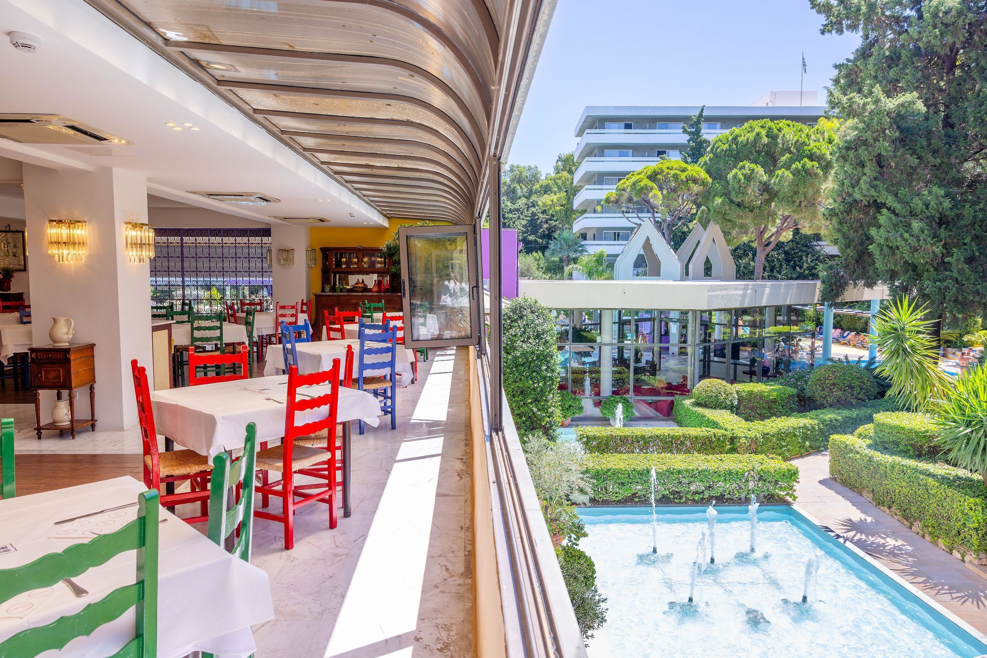 Un restaurant doté d’une terrasse, d’une piscine et offrant une vue sur un bâtiment moderne et des arbres.
