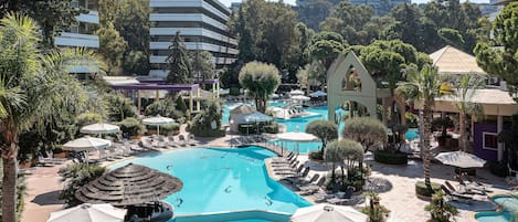 A resort with multiple swimming pools, sun loungers, umbrellas, and lush greenery.