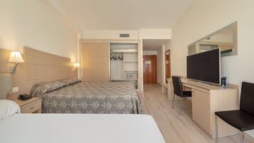 Habitació d'hotel amb llit, taula de nit, làmpada, escriptori amb cadira, televisió i armari.