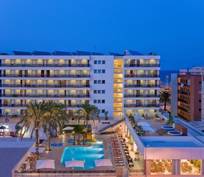 Un hotel con varios balcones, piscina y zonas de estar al aire libre.