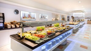A buffet setup with various food items, a clock, and framed pictures on the wall. - Hotel RH Bayren Parc By Hoteles RH (Gandia)