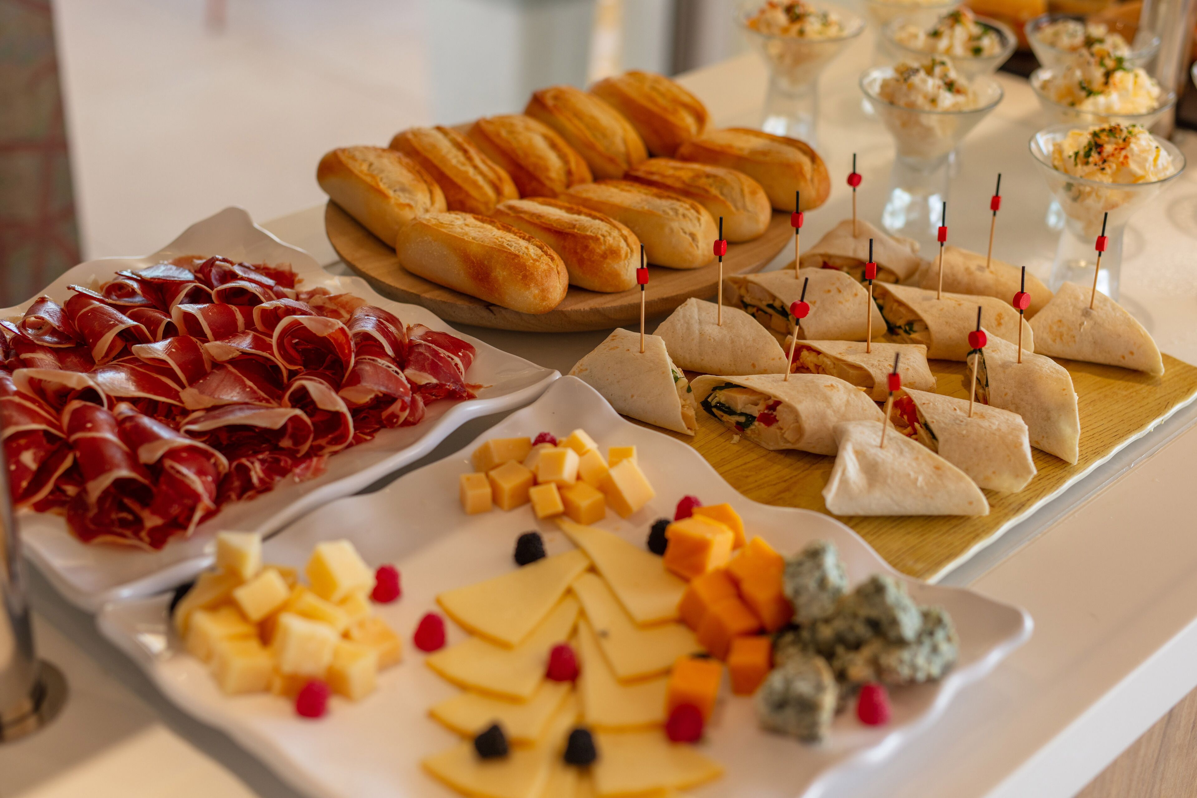 A buffet with various food items including meats, cheeses, and pastries.