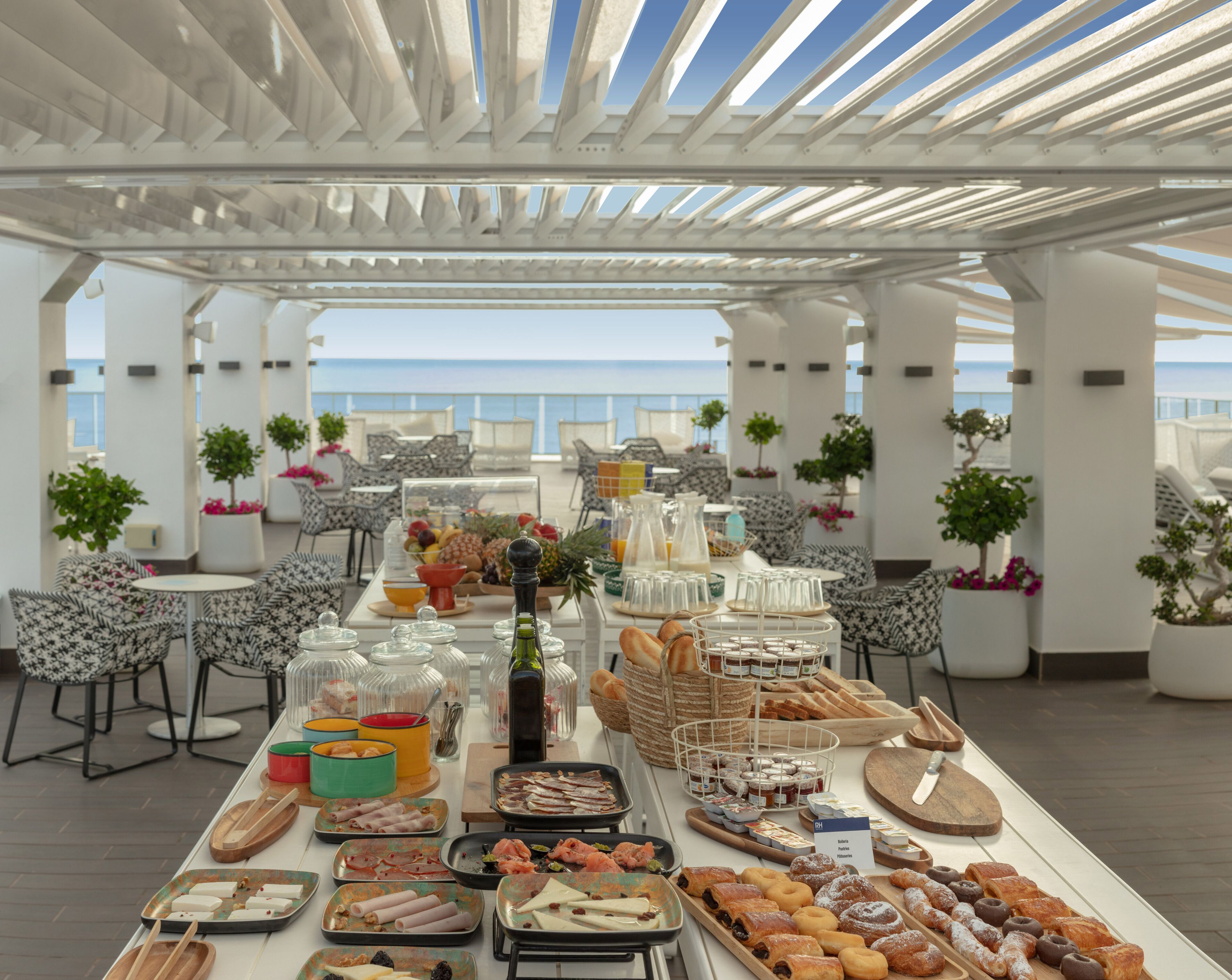 A buffet table with various food items and a view of the sea in the background.