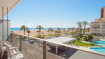 Un balcón con vistas a una playa, una piscina y un edificio con balcones.
