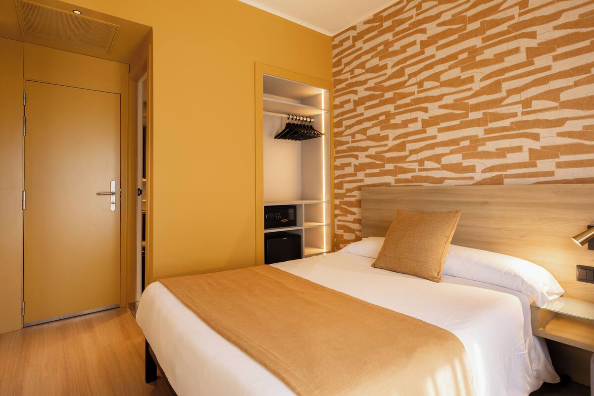 Una habitación de hotel con cama, armario, estantería empotrada y pared con diseño.