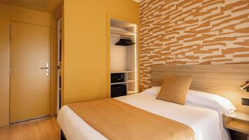 Una habitación de hotel con cama, armario, estantería empotrada y pared con diseño.
