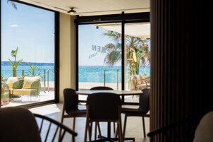 A room with a large glass window overlooking a beach and the sea.
