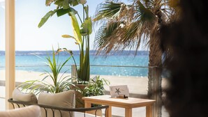 Un balcón con vista a la playa, una mesa de madera decorada con una estrella de mar y una silla con cojines.