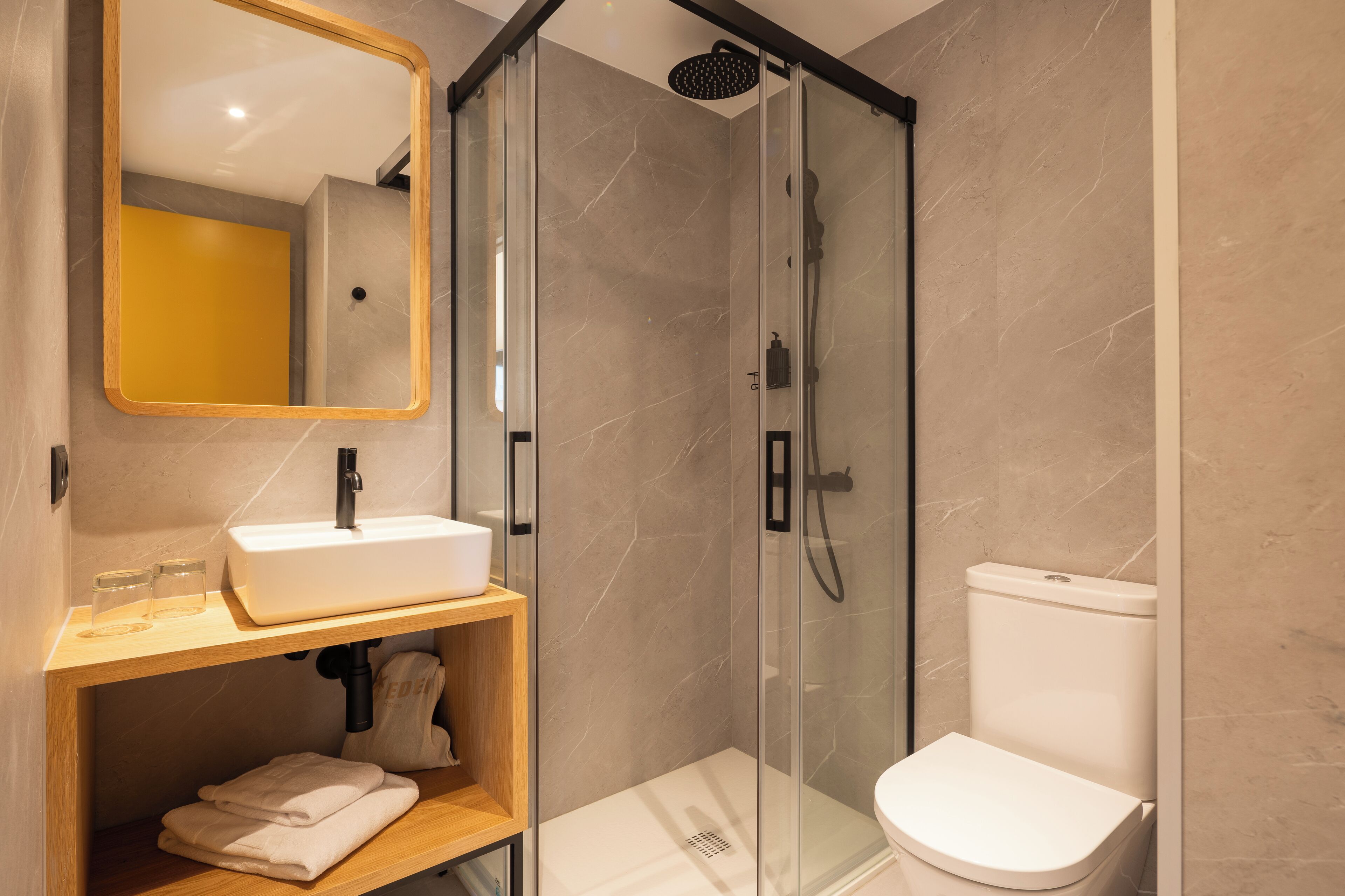 A modern bathroom with a glass-enclosed shower, a white sink, and a toilet.