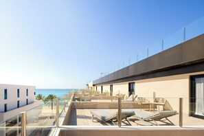 A rooftop terrace with sun loungers, a glass balustrade, and a view of the sea. - Hotel Eden Palma Playa (Palma de Mallorca)