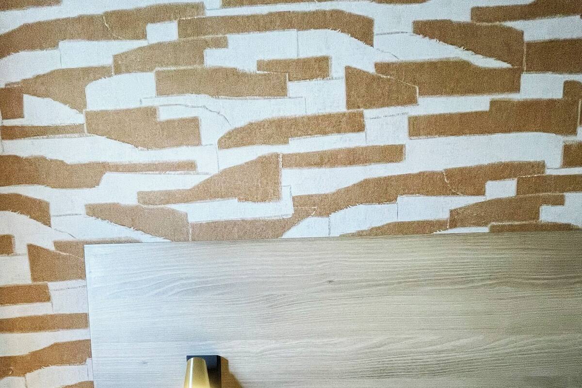 Una cama con cabecera de madera, una mesita de noche con lámpara y una pared con diseño de ladrillo.