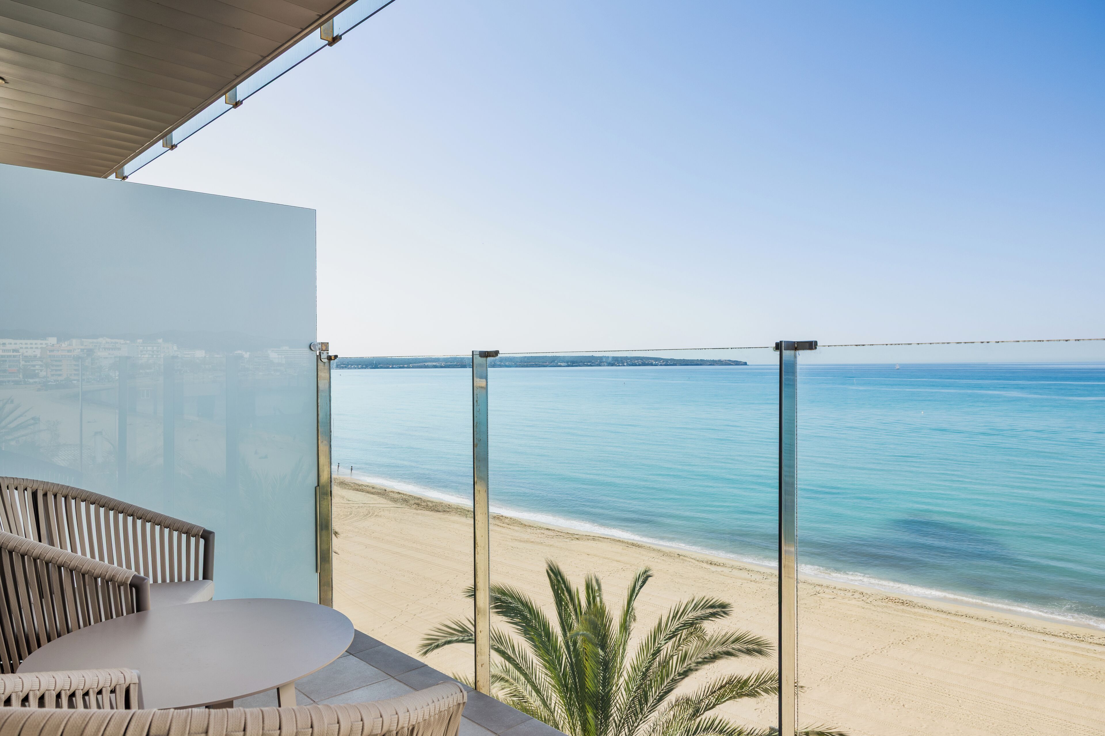 A balcony with a glass railing overlooking a beach.