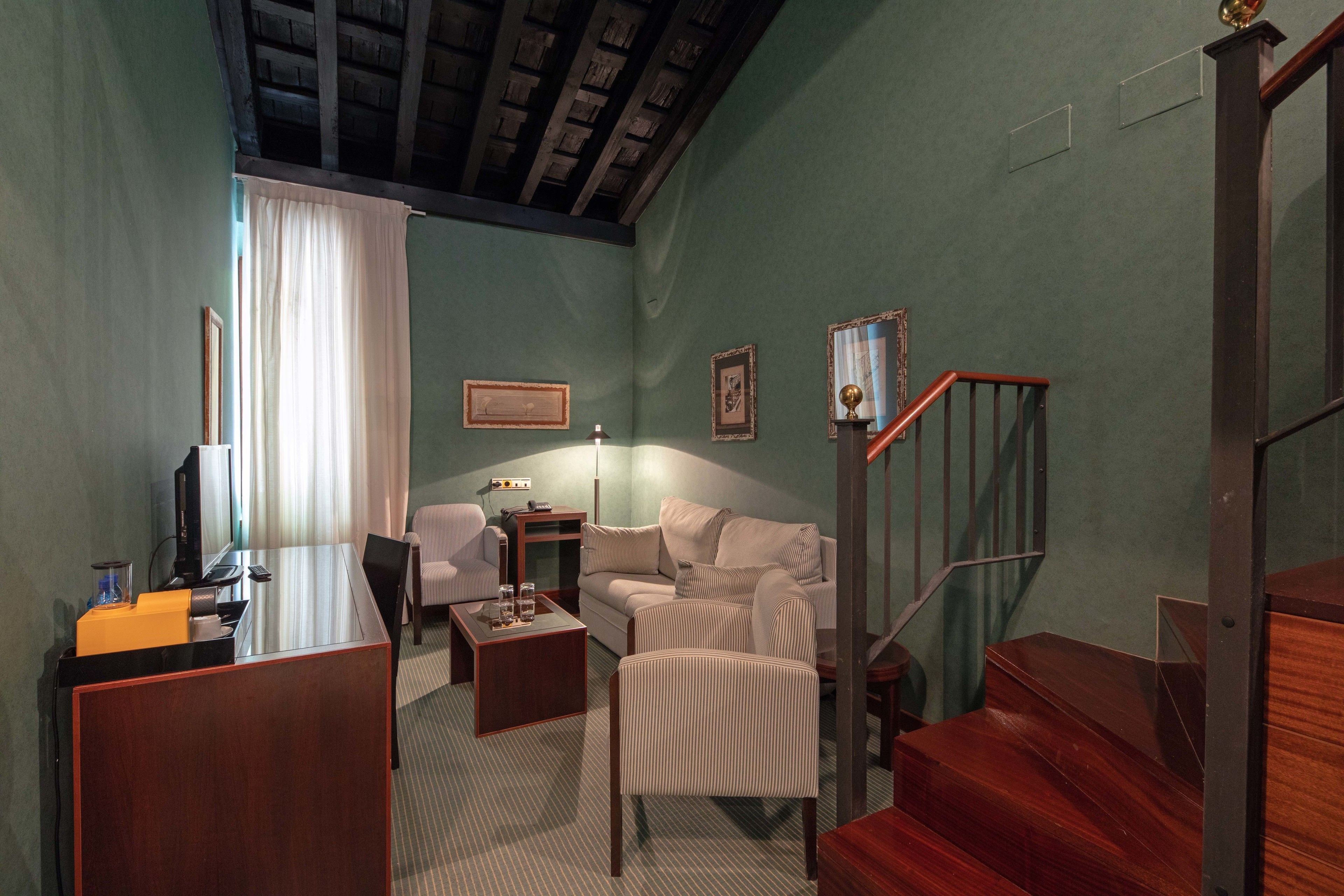 Una habitación de hotel con un escritorio de madera, un sofá, una mesa de centro y una escalera.