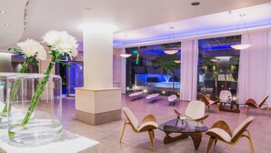 A spacious lobby with a glass table and chairs, a reception desk, and a fountain view.