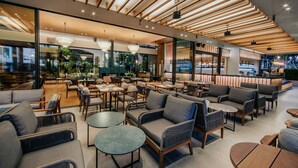 A modern indoor space with wooden slatted ceilings, comfortable seating areas, and large windows providing views of the outside.