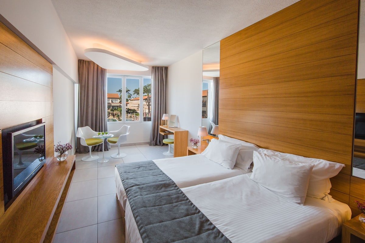 A hotel room with a bed, a desk, a chair, and a TV.