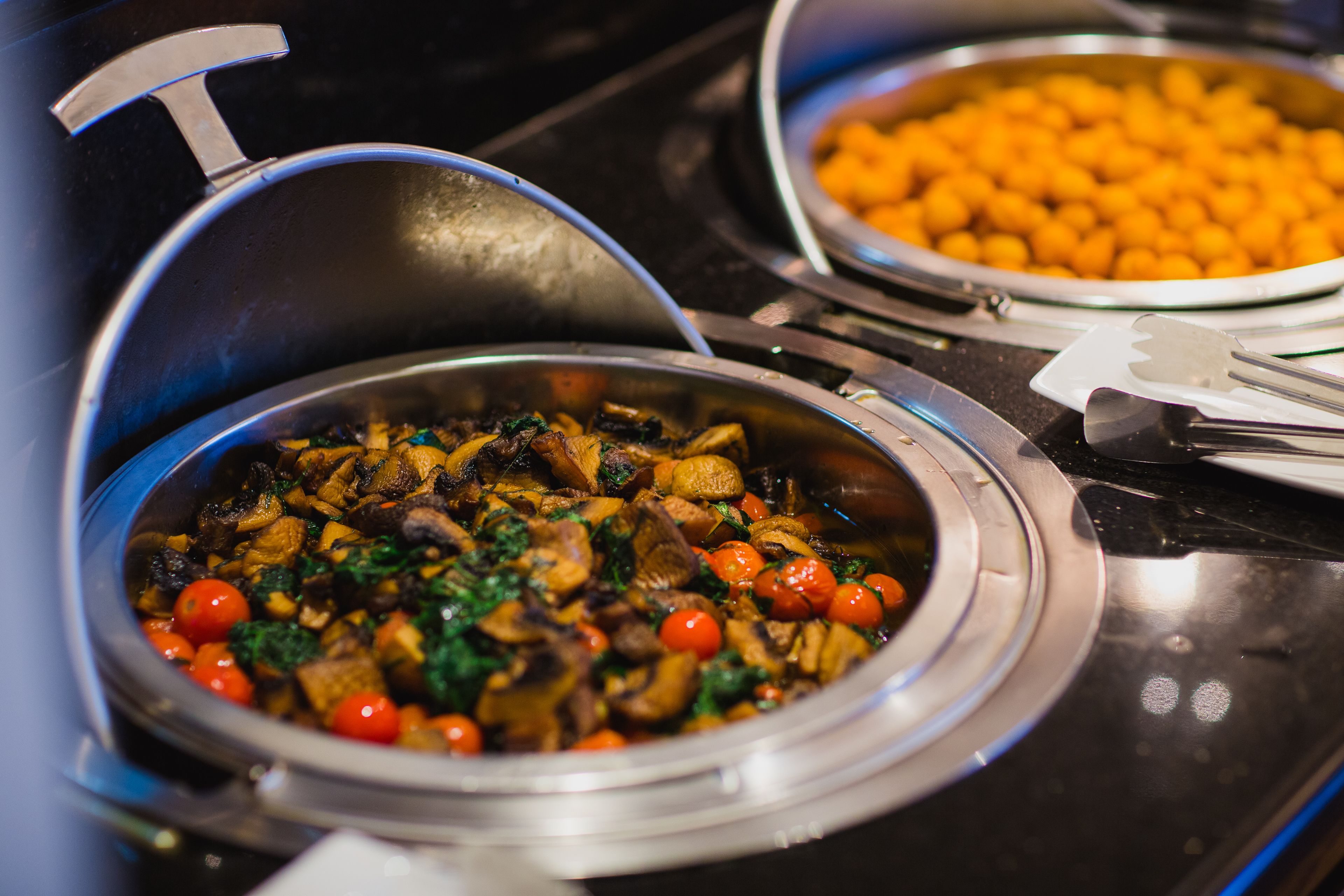 A buffet with various dishes, including a bowl of mixed vegetables and a bowl of orange items.