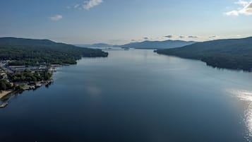 A large body of water surrounded by forested hills, with a small settlement on the left.