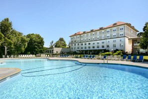 A swimming pool with lounge chairs and a building with multiple windows in the background.