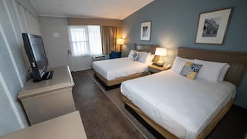 Een hotelkamer met twee bedden, een bureau met een televisie en een raam met gordijnen.