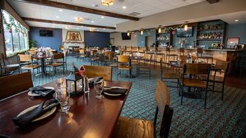 A restaurant with multiple dining tables, chairs, and a bar area.