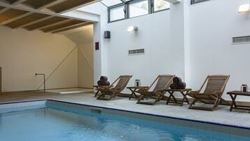 Una piscina con sillones de madera y un techo con vigas de madera.