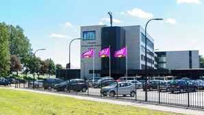 Un hôtel arborant plusieurs enseignes, un parking et une façade de bâtiment moderne.