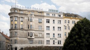 Edifício histórico de um hotel com vários andares, arquitetura clássica e um letreiro chamativo com a palavra 