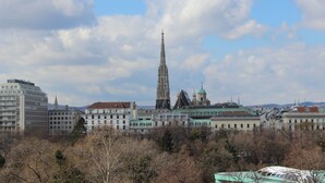 Paisagem urbana com uma imponente torre de catedral, edifícios históricos e uma mistura de arquitetura moderna.