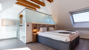 Een moderne slaapkamer met een schuine kap, een bed met hoofdeinde met een bergmotief, en een dakraam.
