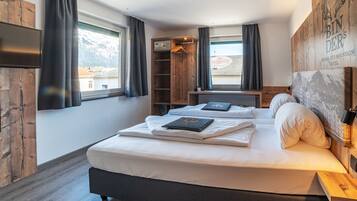 Un dormitorio con una cama grande, un armario de madera y vistas a las montañas a través de la ventana.