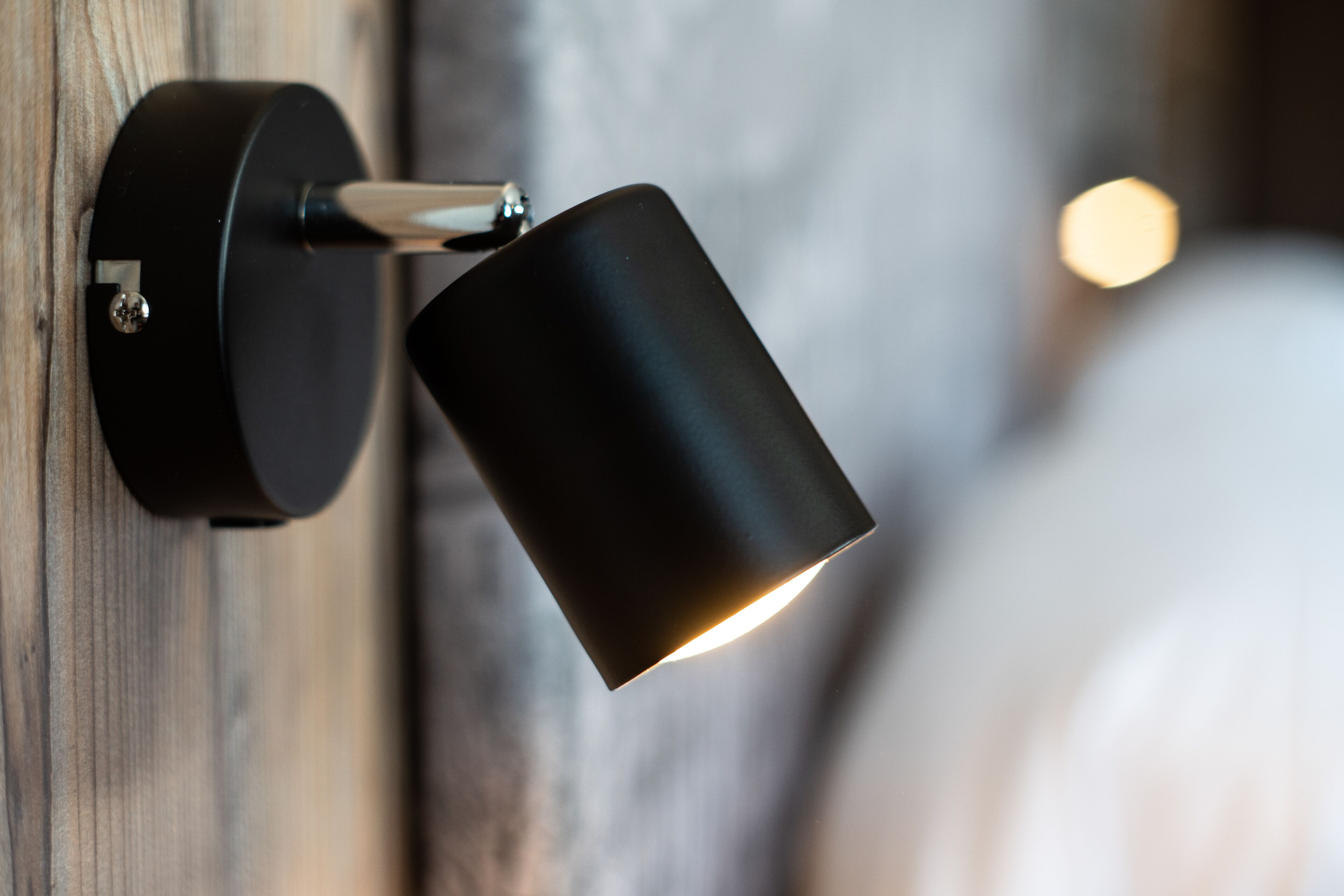 En väggmonterad lampa med en cylindrisk skärm.
