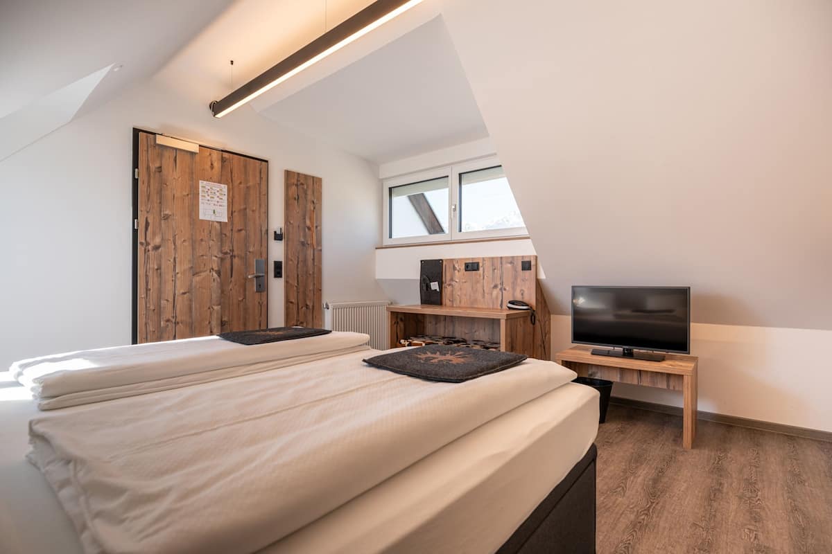 Un dormitorio moderno con una cama grande, televisión y detalles de madera.