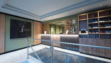 Een moderne hotel lobby met een receptiebalie, een grote poster en een boekenpresentatie.