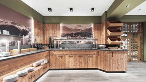 Een moderne keuken met houten kastjes, een centraal eiland en een groot raam met uitzicht op de bergen.