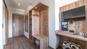 A room with a wooden desk, a television, and a bench.