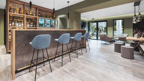 Een moderne bar met een marmeren toonbank, barstoelen en verschillende drankflessen.