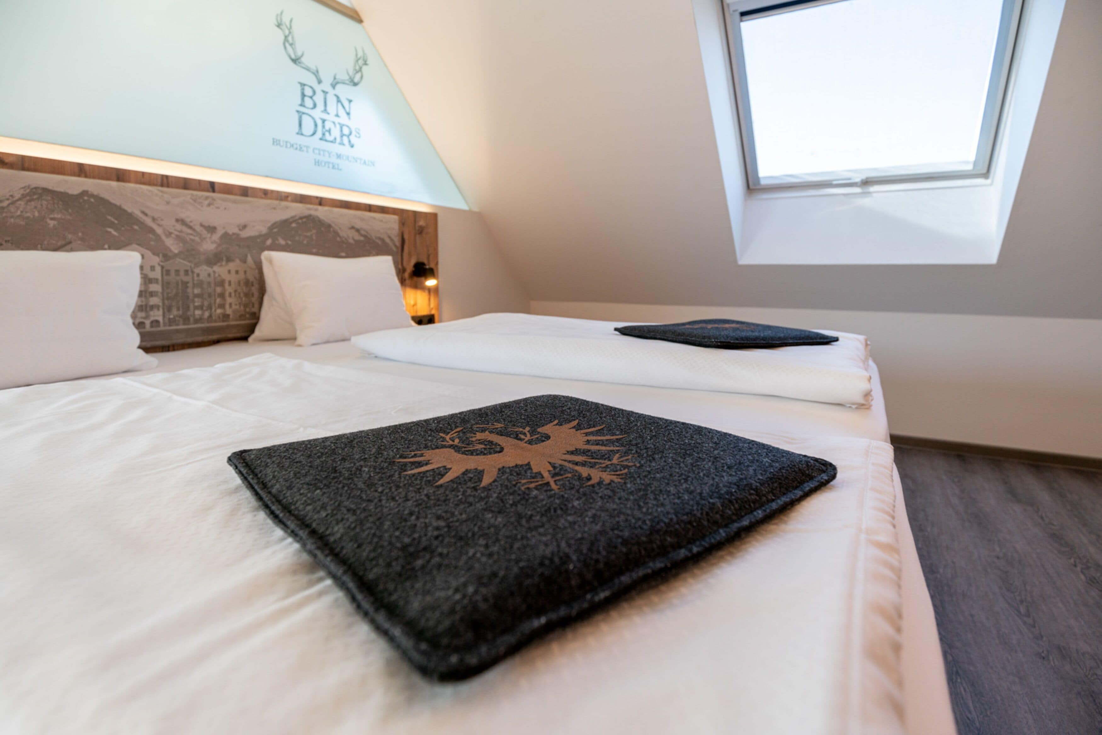 Une chambre d’hôtel avec un lit, une lucarne et un panneau fixé au mur.