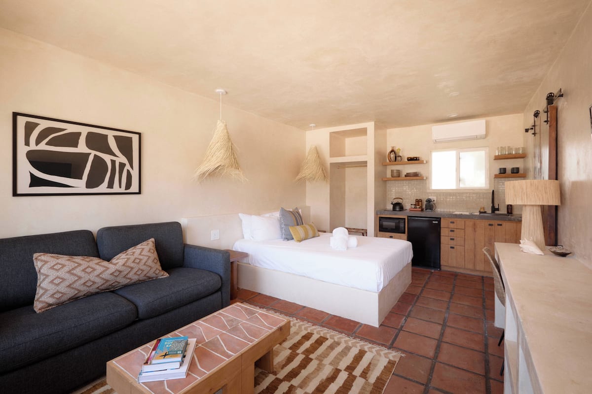 A compact living space with a bed, sofa, and kitchenette.