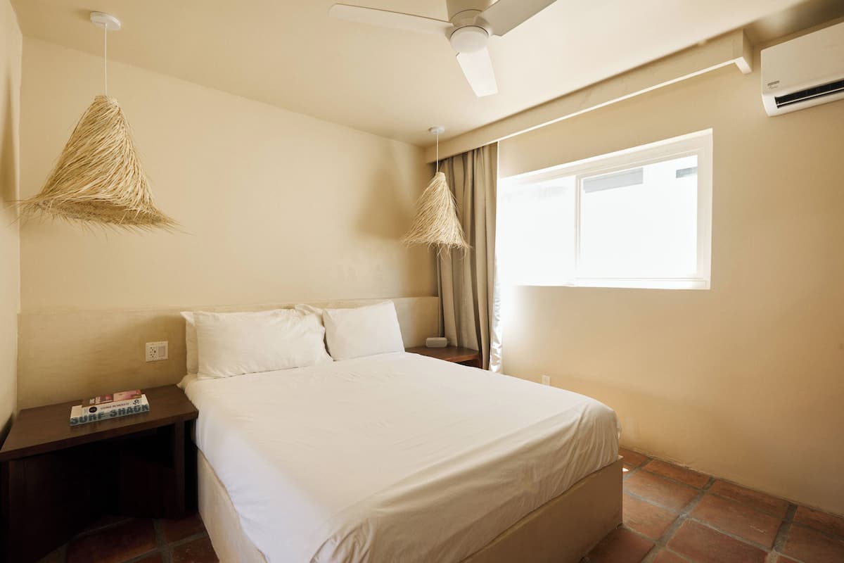 A bedroom with a bed, a nightstand, a ceiling fan, and a window.
