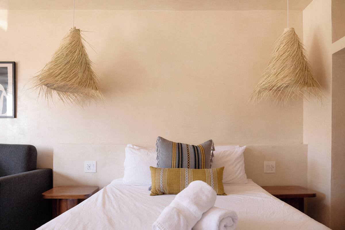 A neatly made bed with white linens, two bedside tables, and a chair.