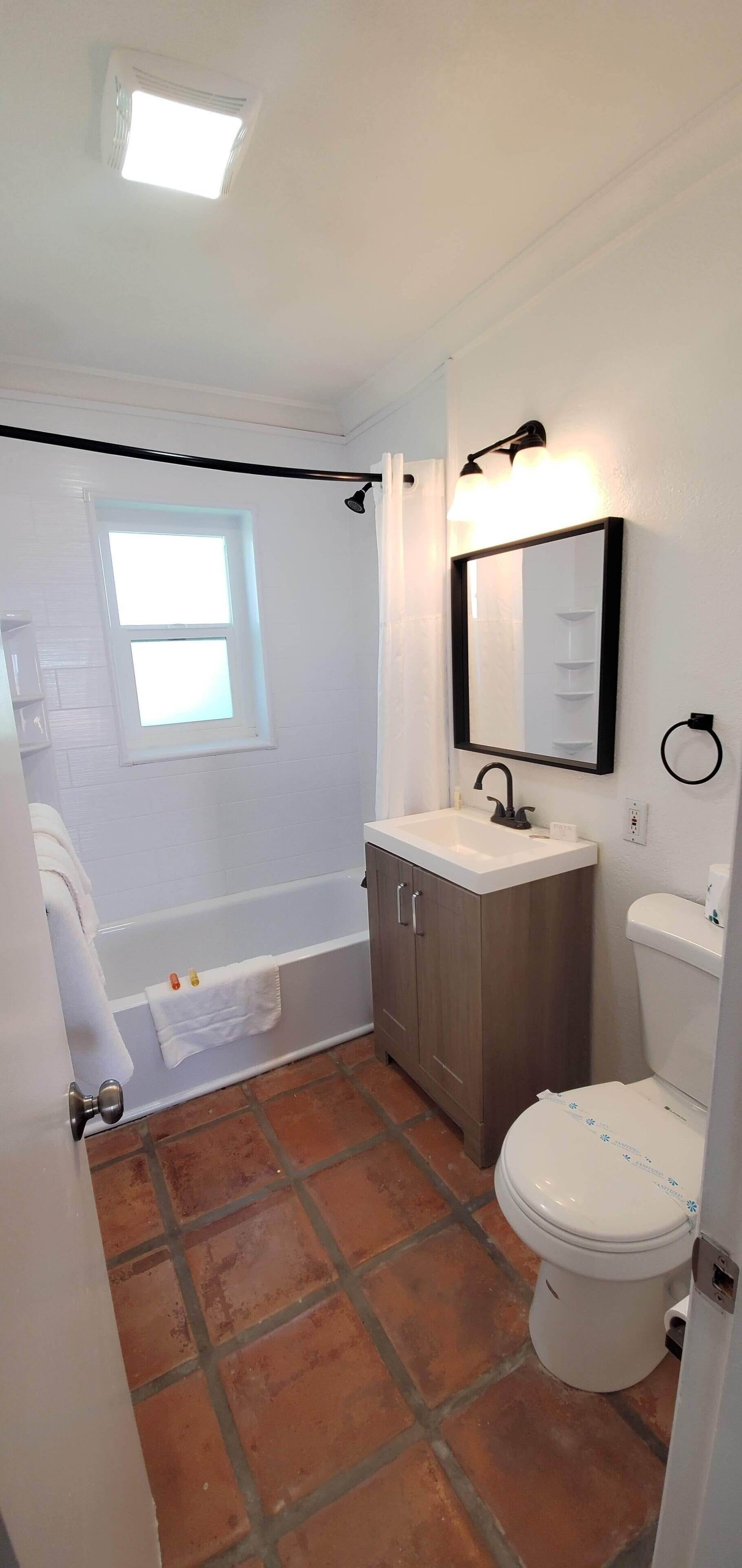 A bathroom with a bathtub, a toilet, a sink, and a mirror.